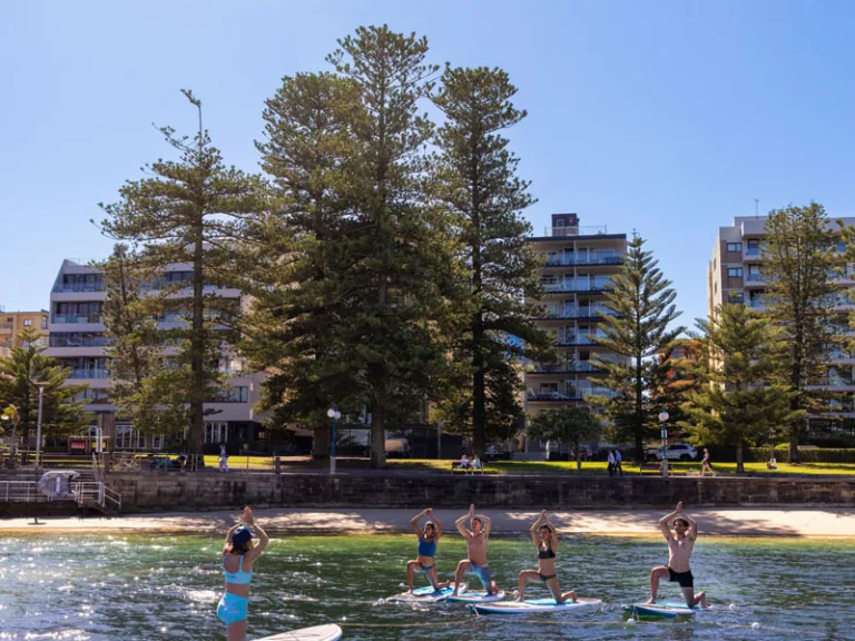 Friends having fun with yoga moves on a paddle board with Flow MOcean, Manly