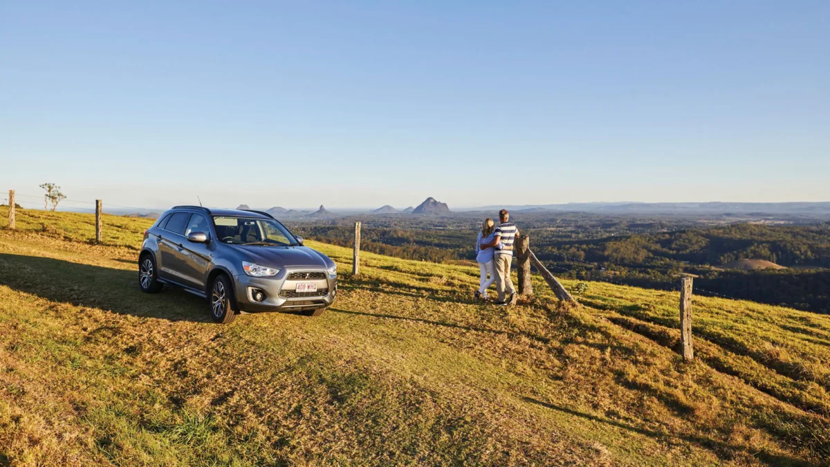 A car and a couple looking out over the Glasshouse Mountains