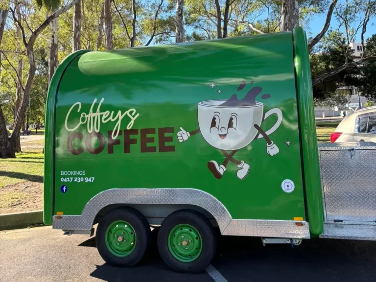 A green mobile coffee trailer parked outdoors.